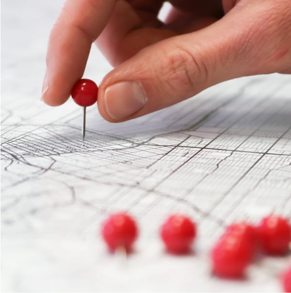Photo of a hand placing a pushpin on a geographical map.